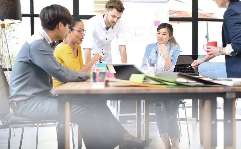Equipe da Clicka Gráfica reunida em mesa de trabalho analisando projetos gráficos